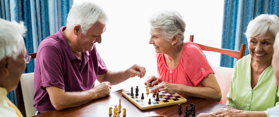 Older adults playing chess on a sunny day.